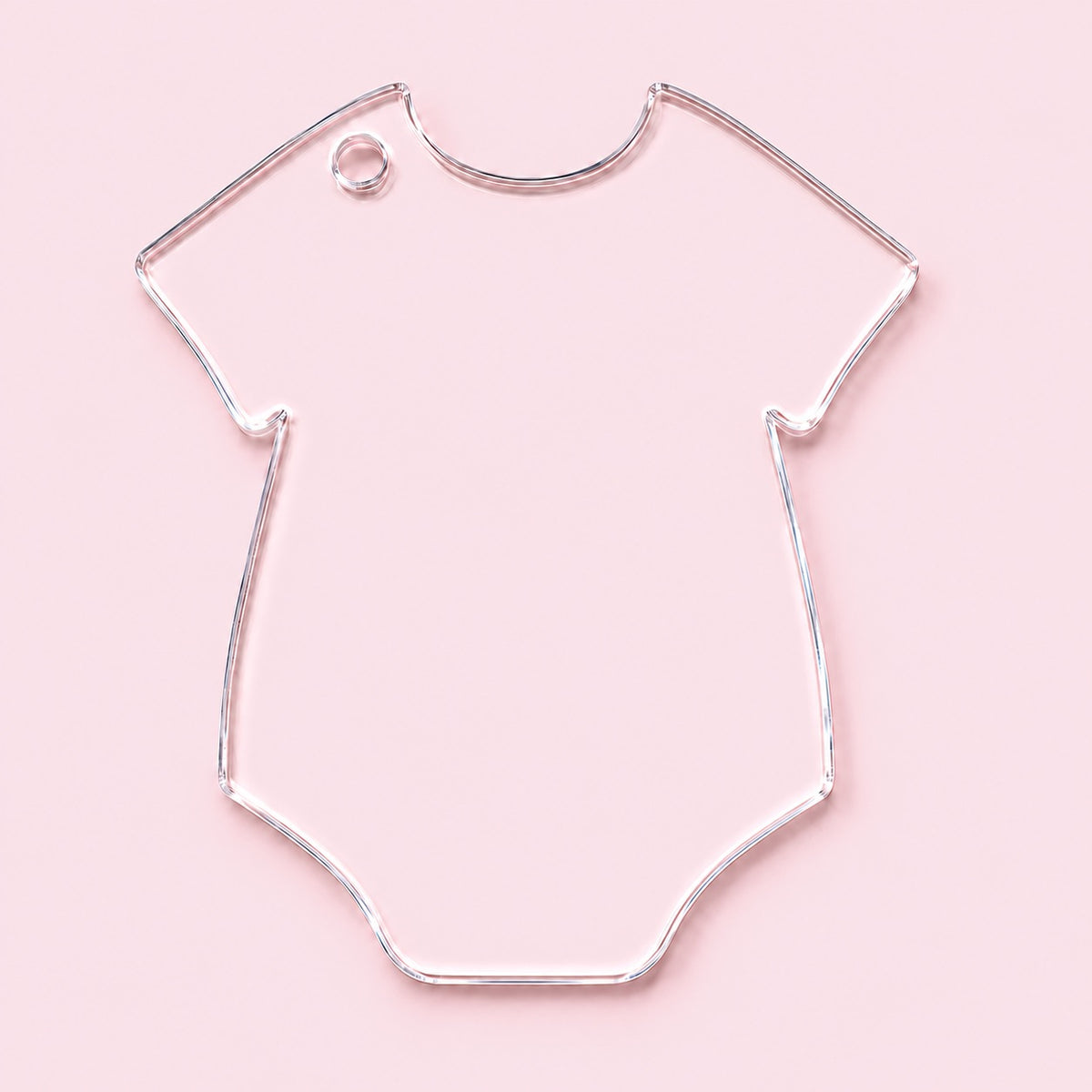 Clear onesie-shaped acrylic blank with an upper left shoulder hole, shown on a pink background.