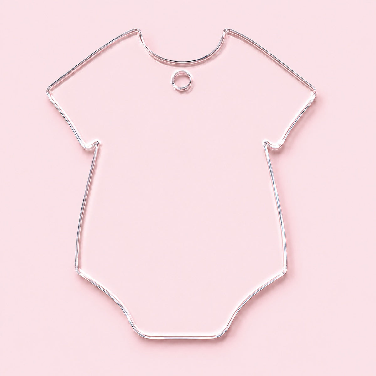 Clear onesie-shaped acrylic blank with a top center hole below the neckline, shown on a pink background.